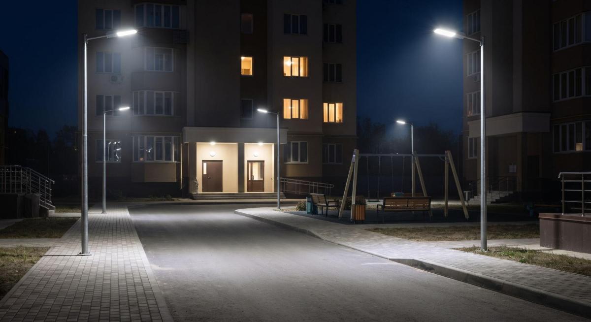 Вуличні світильники на опорах освітлюють двір, вхід у під'їзд і дитячий майданчик уночі